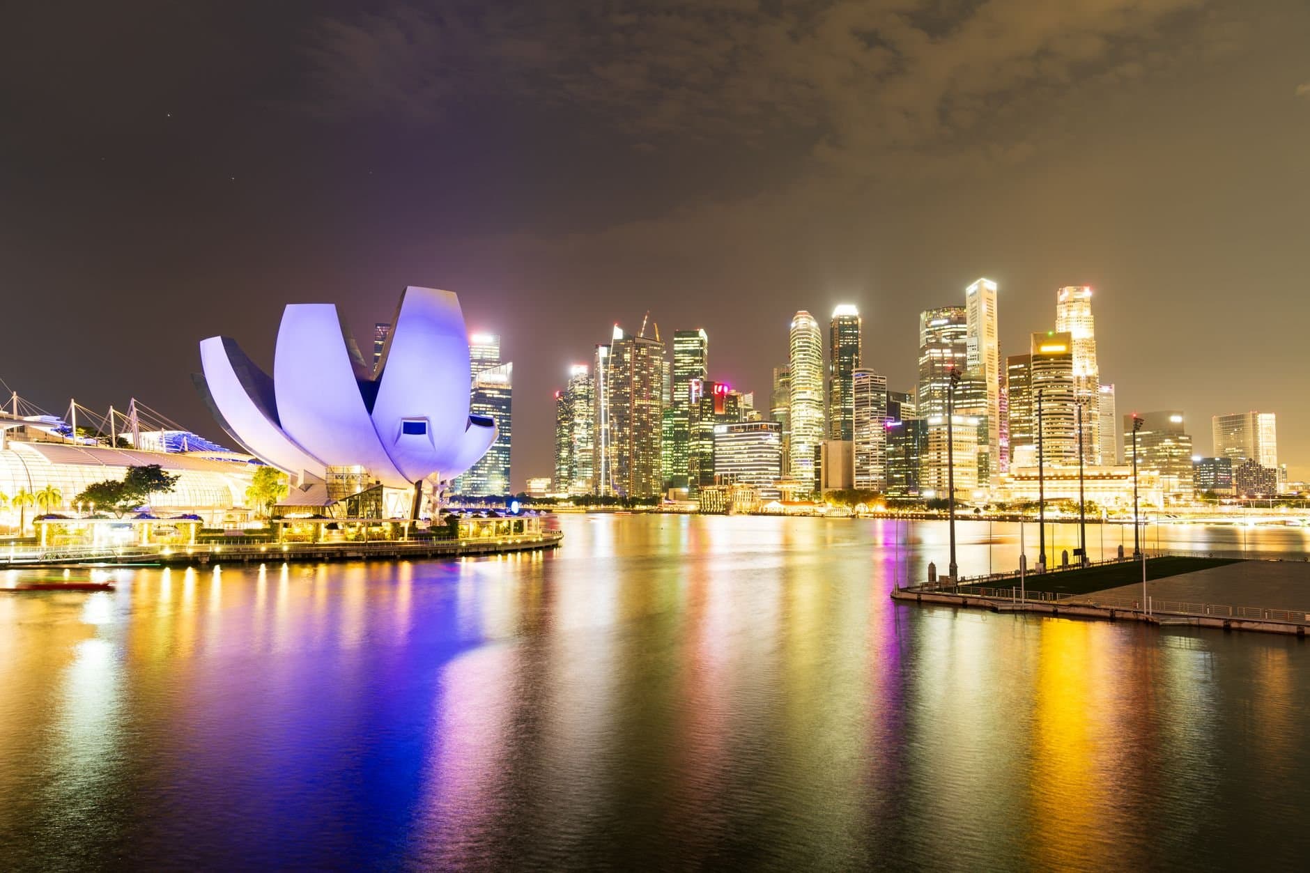 Night view of Singapore's illuminated skyline and Marina Bay Sands, reflecting vibrant city lights.