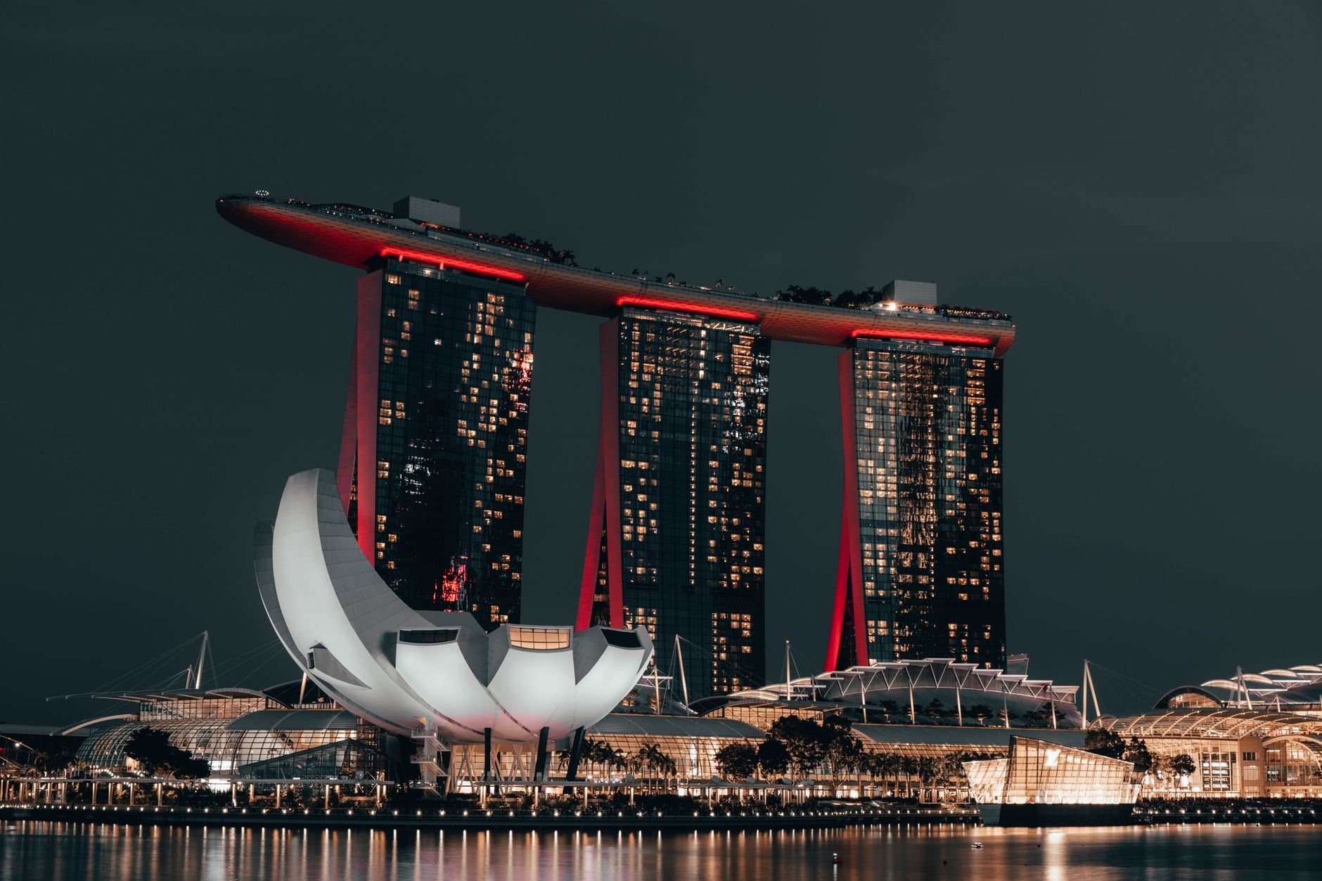 Dramatic night view of Marina Bay Sands, Singapore, with glowing cityscape and reflection.