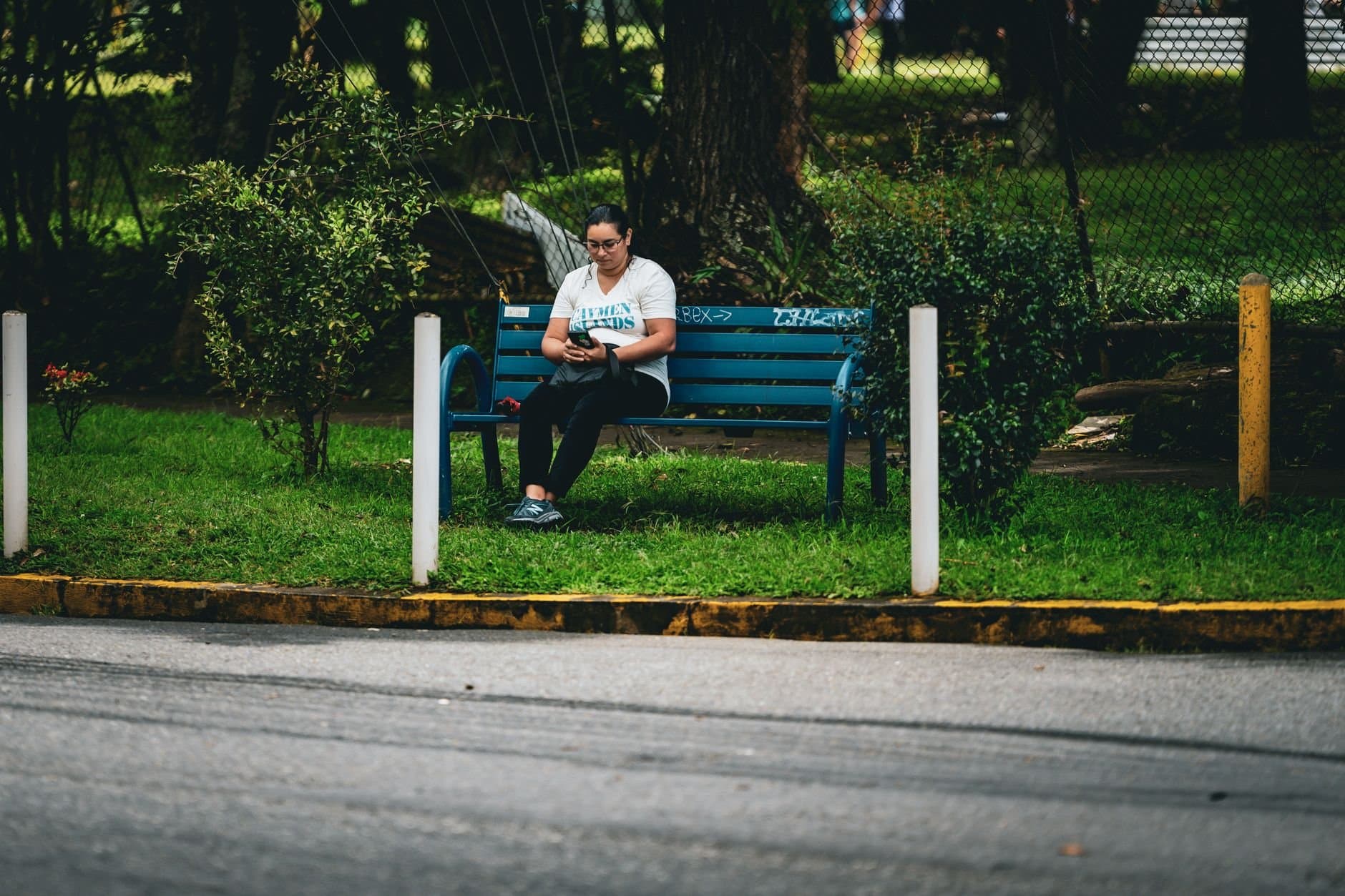 A woman sits on a park bench in San José, Costa Rica, enjoying a peaceful moment outdoors.