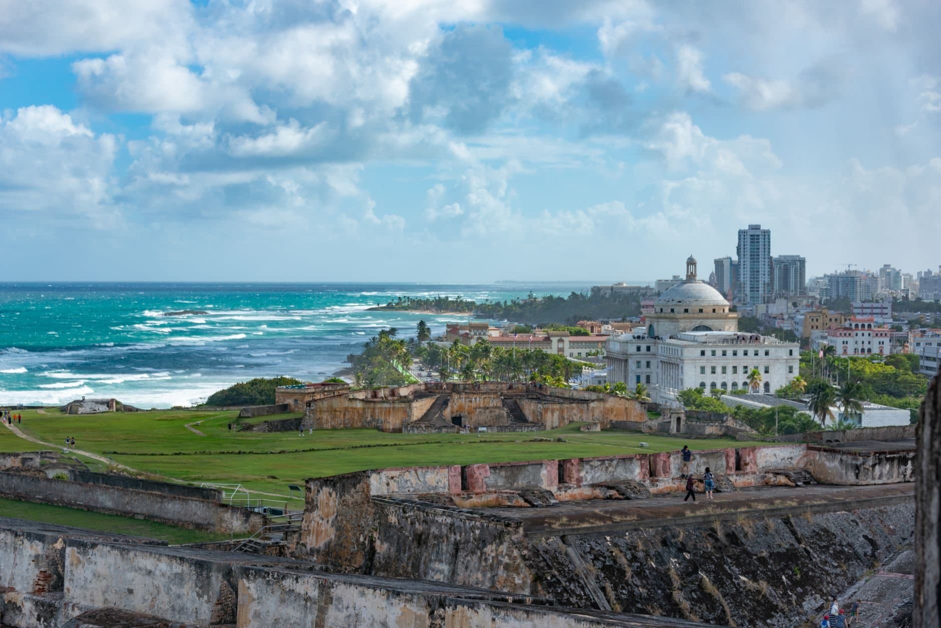 Explore the stunning view of San Juan's historic fort with ocean backdrop under a vibrant sky.