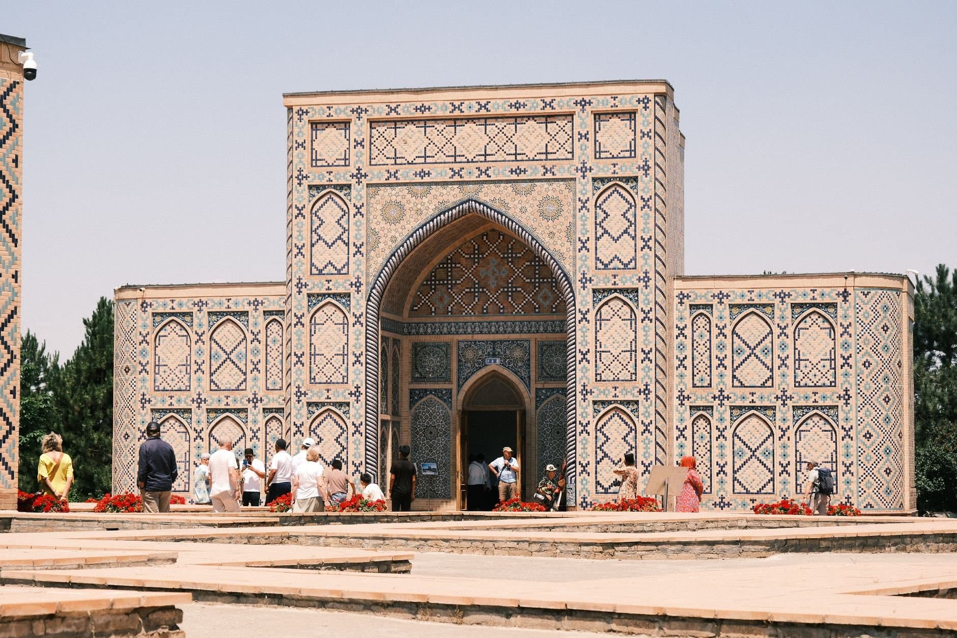 Beautiful historical mausoleum with intricate tilework and tourists exploring outside on a sunny day.