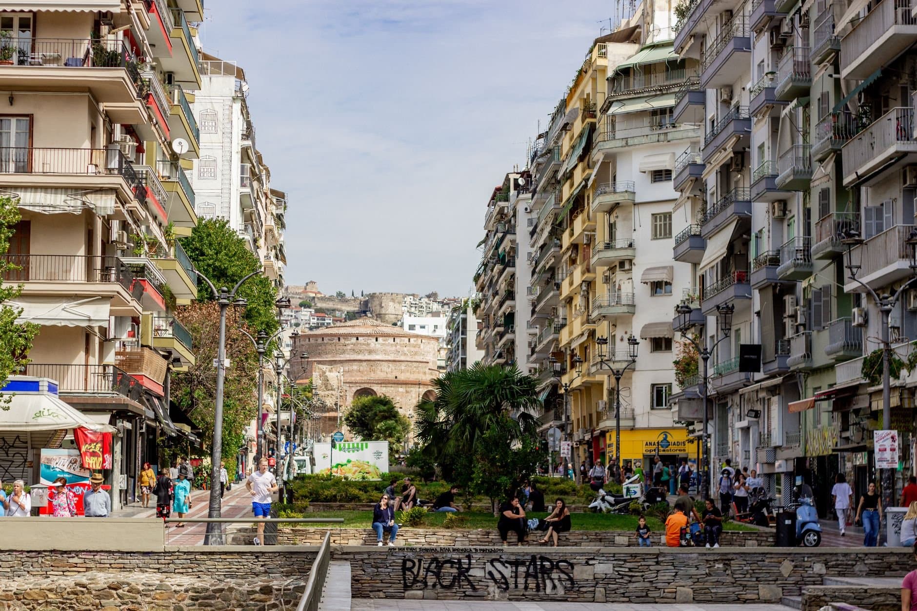 Bustling street scene in Thessaloniki, Greece with historic Rotunda in the background.
