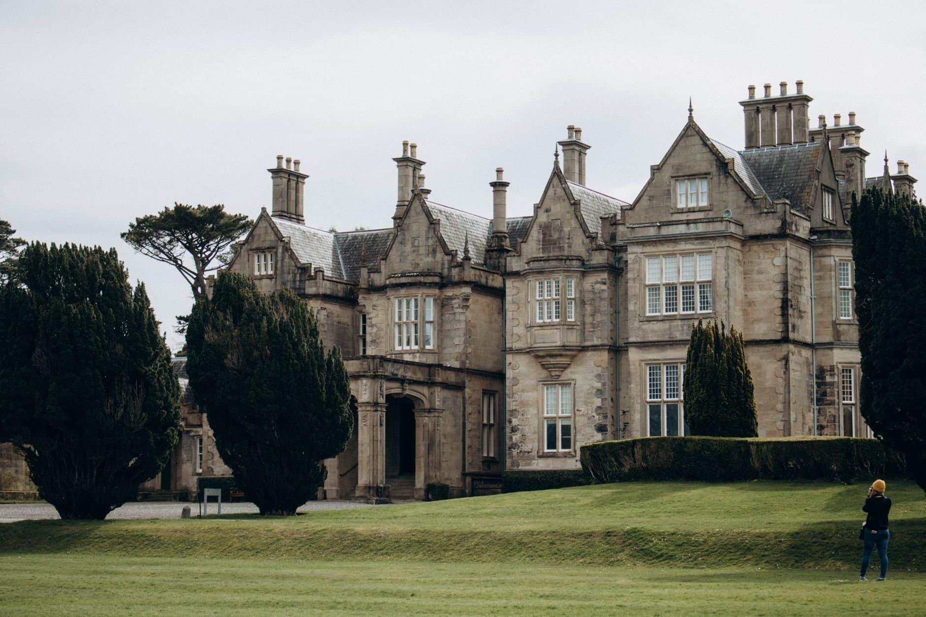 Historic Muckross House in Killarney, Ireland, surrounded by lush greenery.