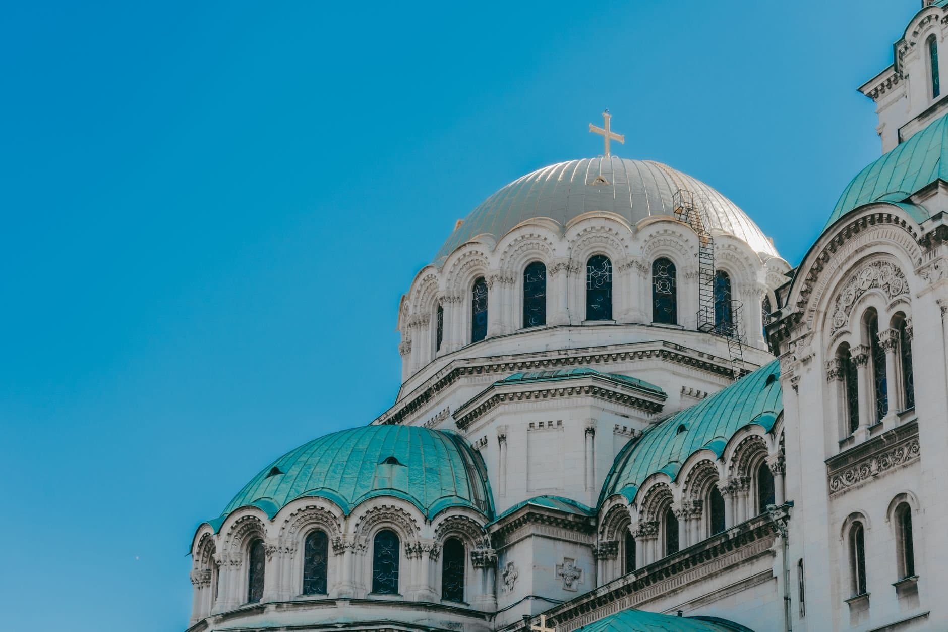 The iconic domes of Alexander Nevsky Cathedral against a clear blue sky in Sofia, Bulgaria.