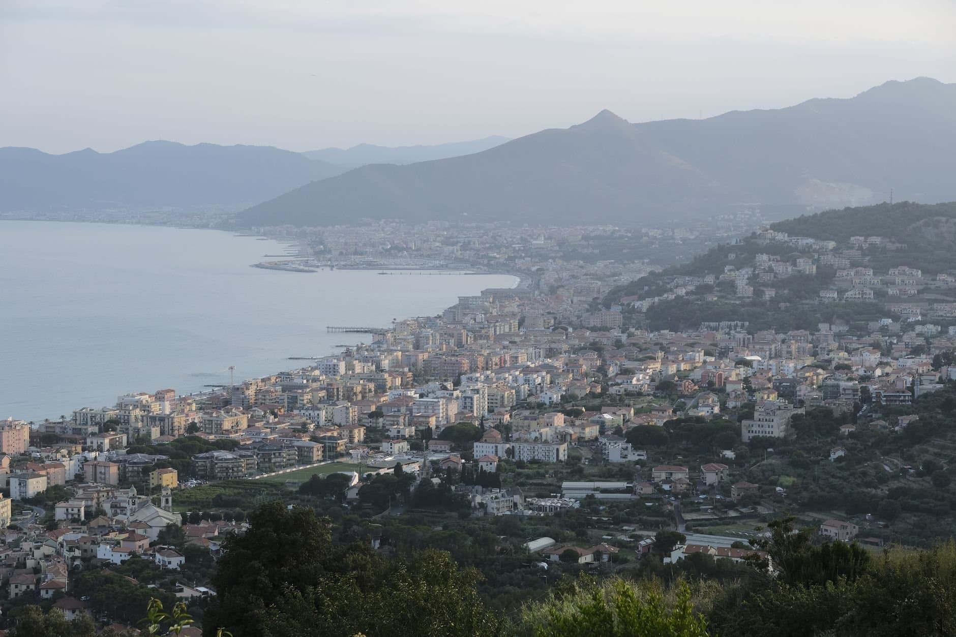 A breathtaking view of a coastal city in Italy with mountains and sea in the background.