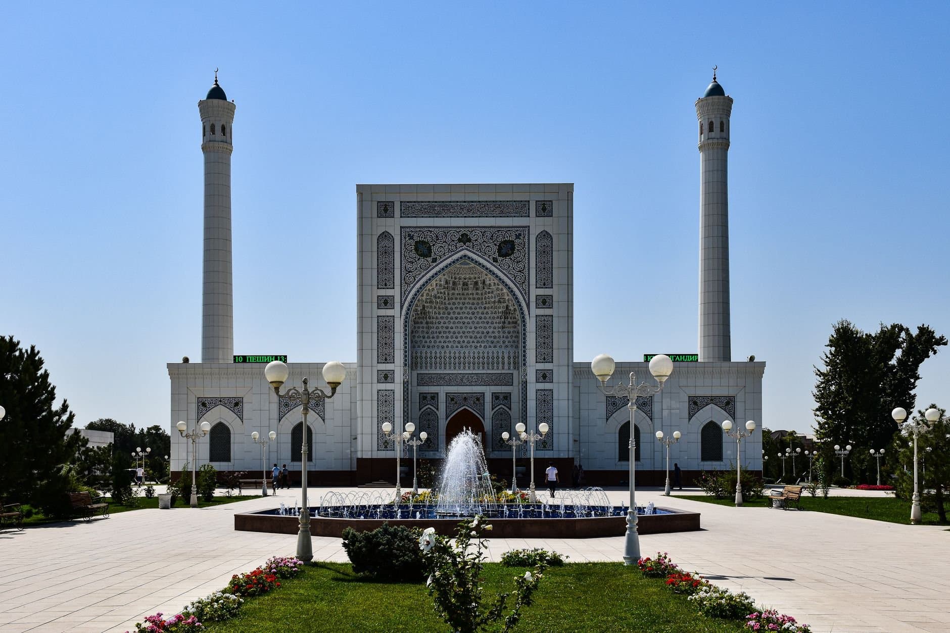Beautiful mosque with intricate design and fountains under a clear blue sky.