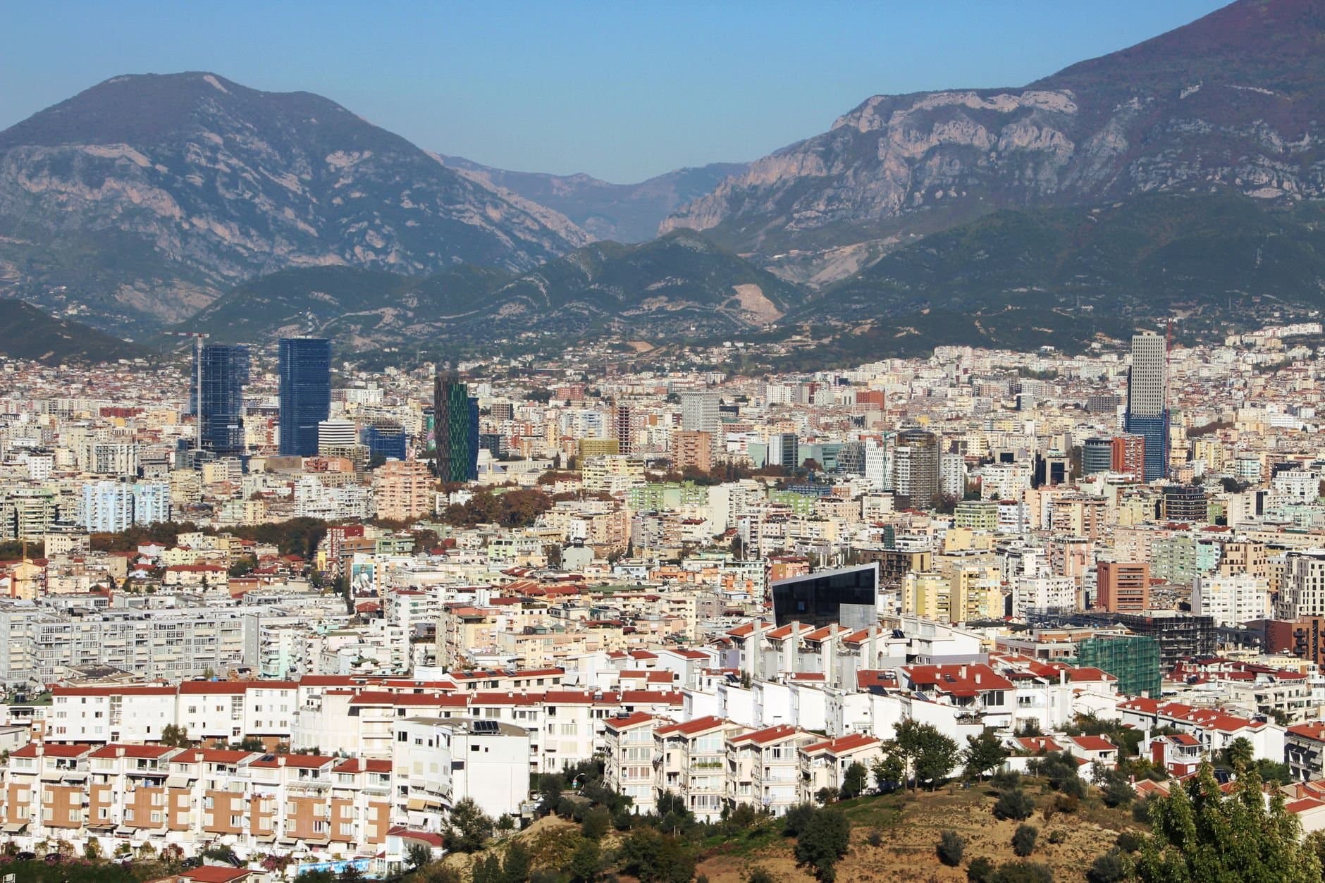 Aerial view of Tirana, Albania, featuring urban landscape and distant mountains.