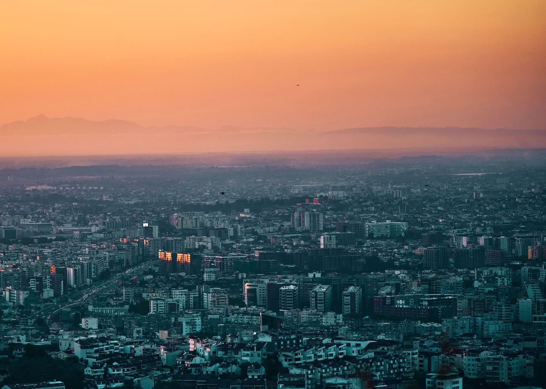 A stunning aerial shot of Tirana, Albania with vibrant orange skies during sunset. Perfect for travel and cityscape enthusiasts.