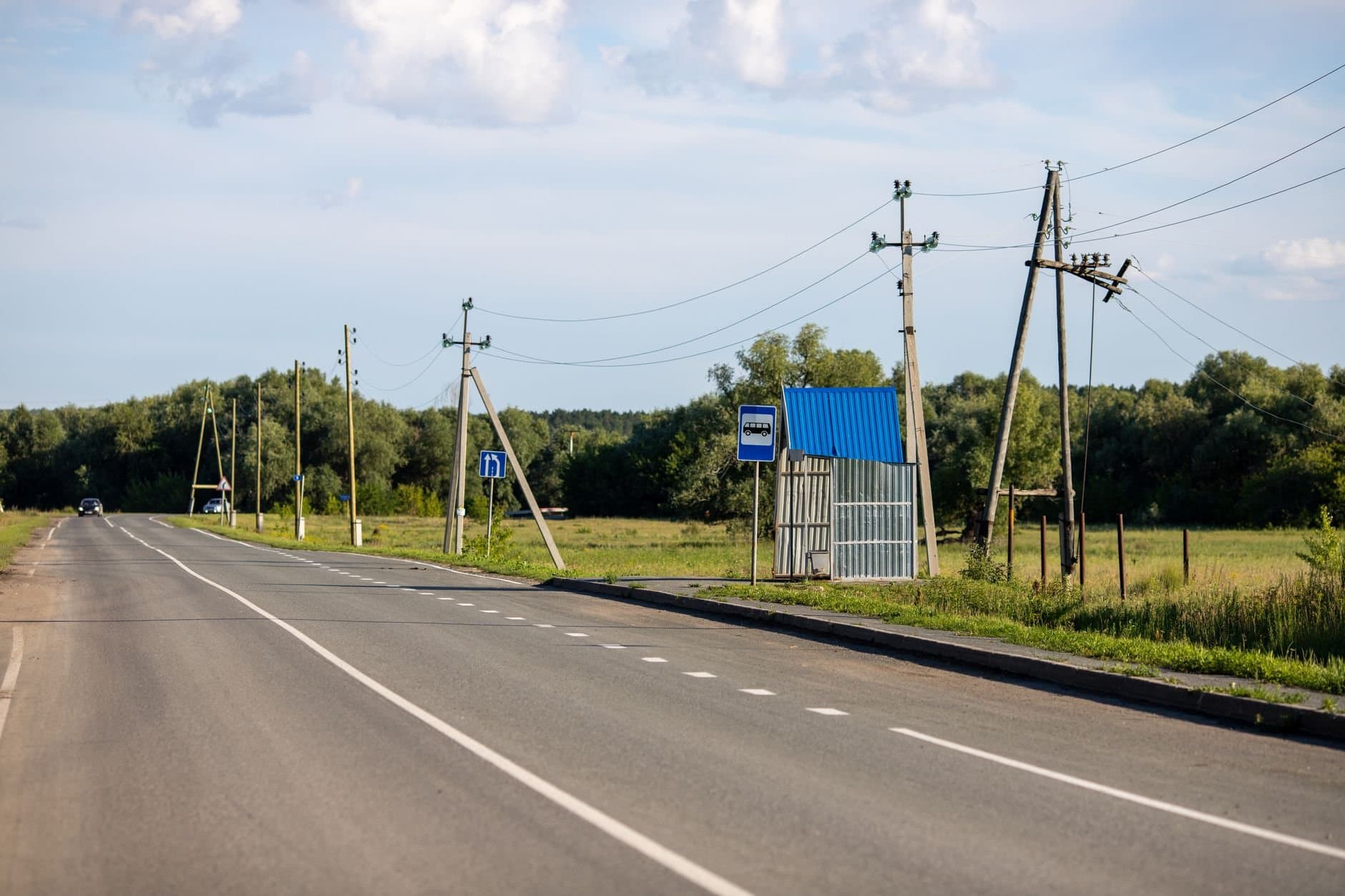 Scenic rural road in Sinitsyna, Tyumen with utility poles, fields, and clear blue sky.