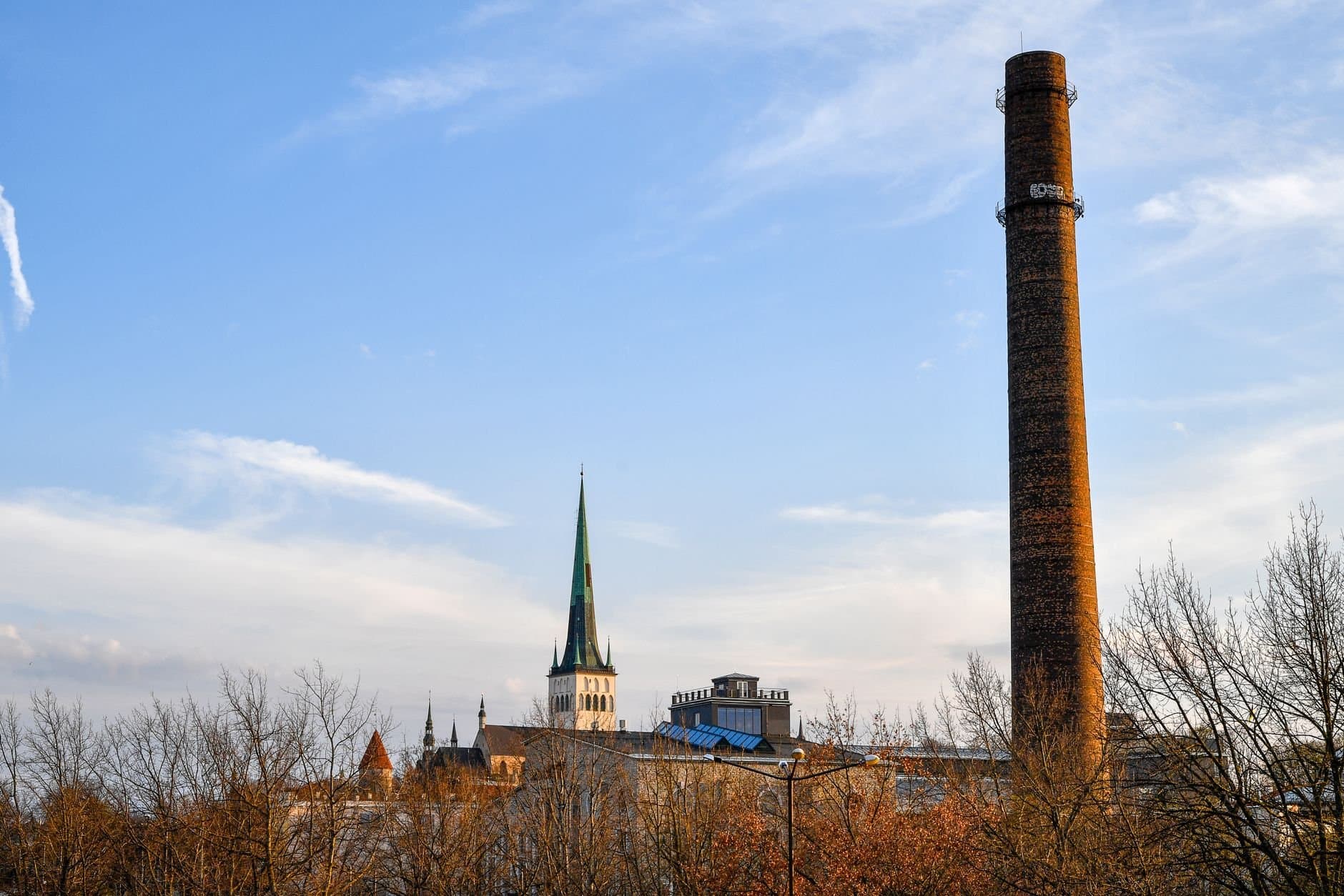 Scenic view of St. Olaf's Church and industrial chimney in Tallinn, Estonia during sunset.