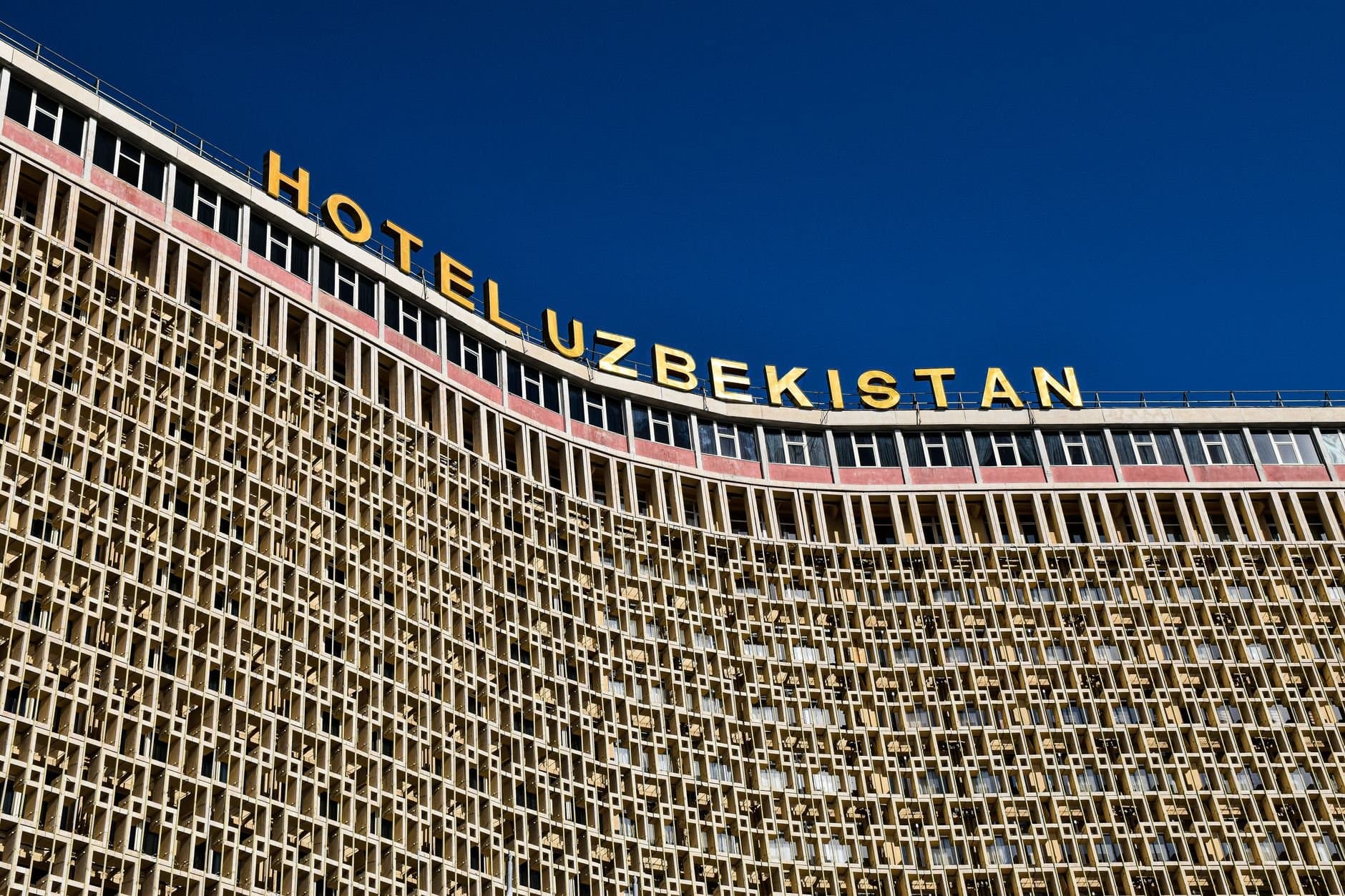 Low angle shot of Hotel Uzbekistan facade against a clear blue sky.