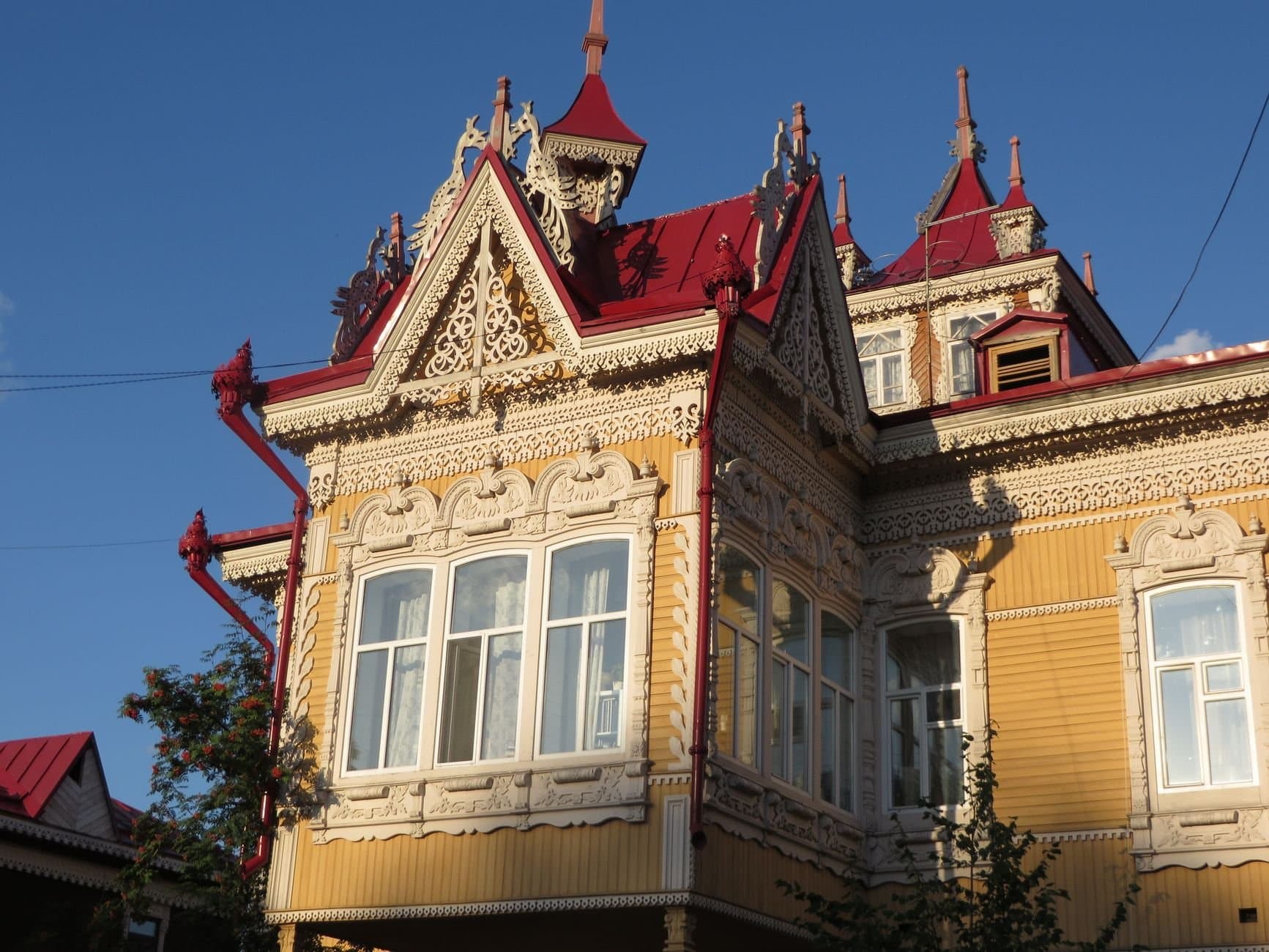 Intricate wooden carvings and red roofs showcase architectural beauty in Tomsk, Russia.