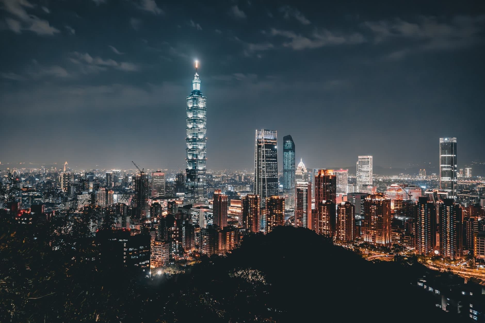 Night view of the Taipei skyline featuring the illuminated Taipei 101 amid modern skyscrapers.