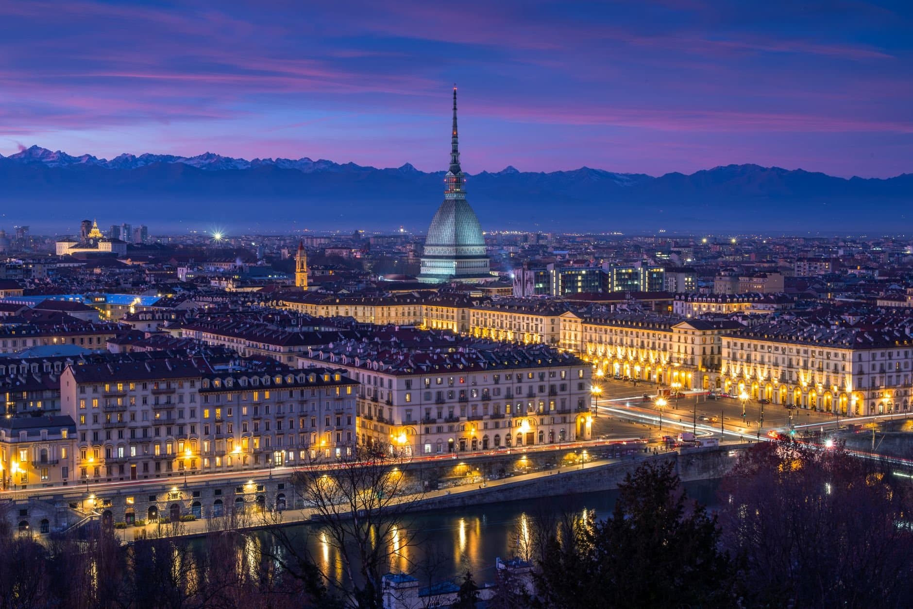 Stunning nighttime view of Turin's cityscape featuring the iconic Mole Antonelliana against a vibrant twilight sky.