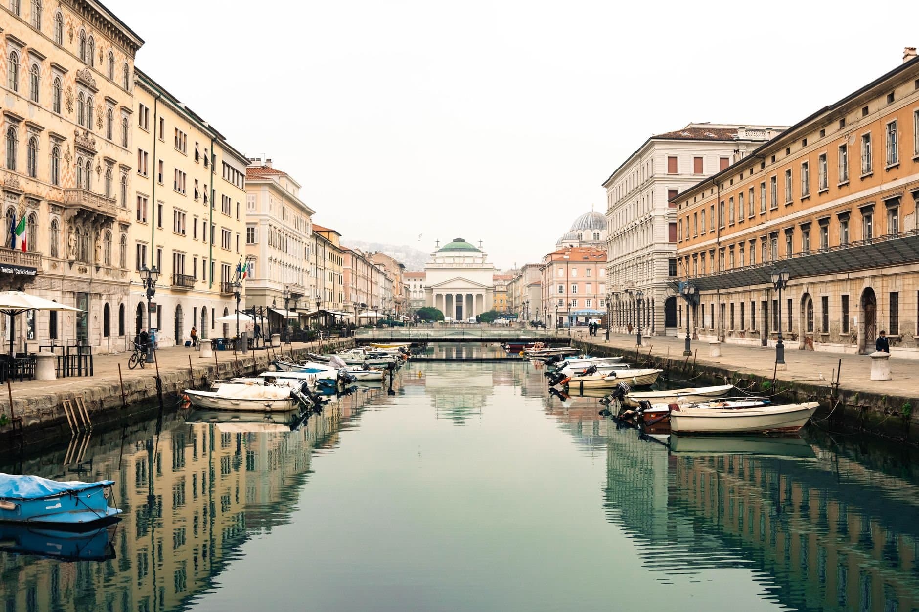 Charming canal with boats in Trieste, Italy showcasing classic architecture and reflections.
