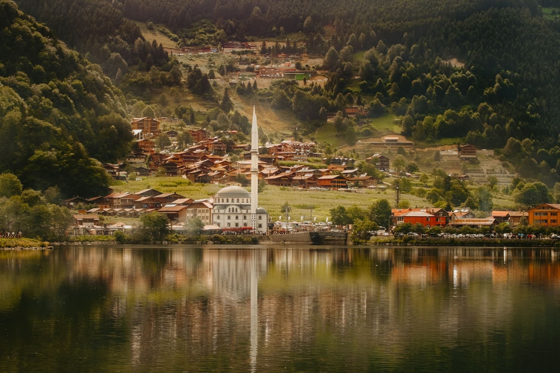 Scenic view of Uzungöl village and mosque reflected in a tranquil lake.