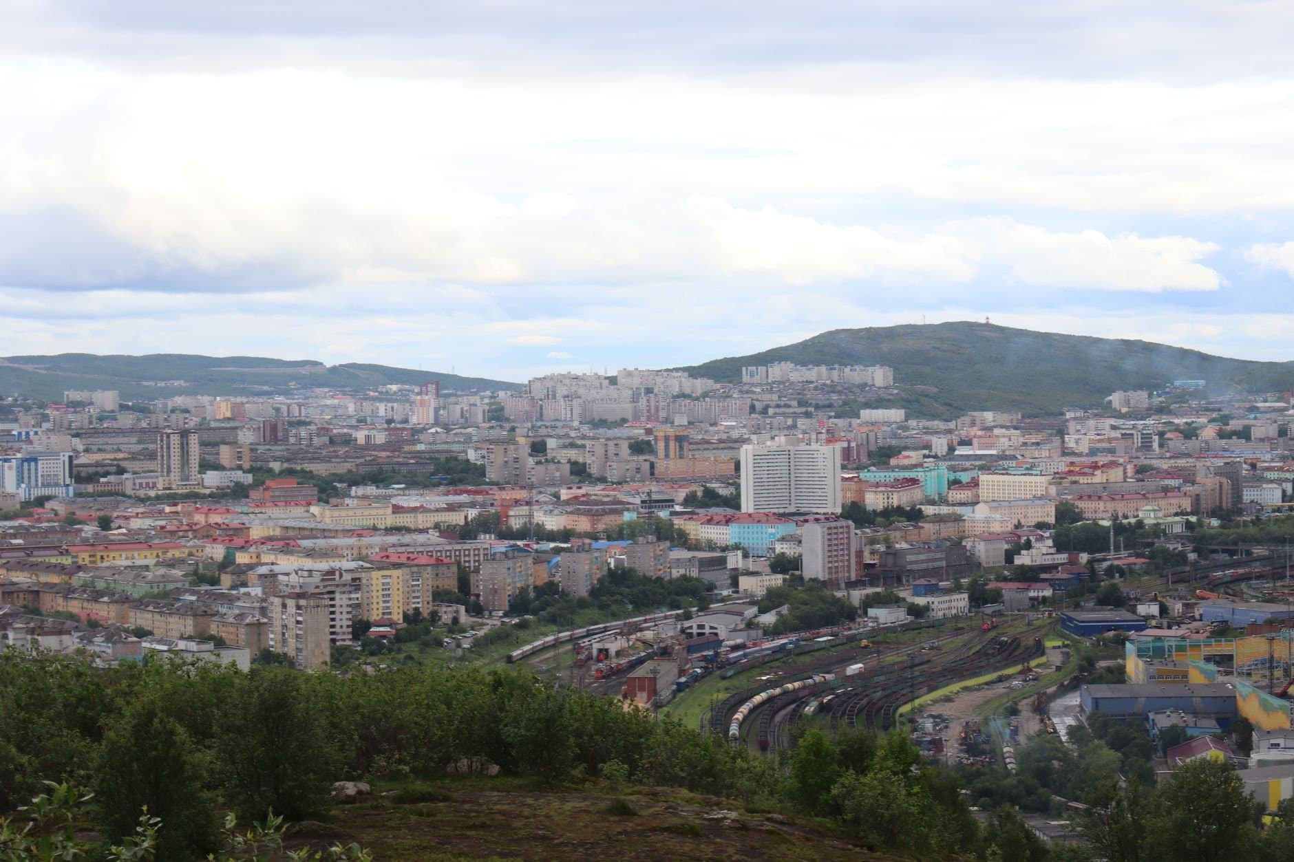 Panoramic view of a cityscape with mountains in the background under cloudy skies.