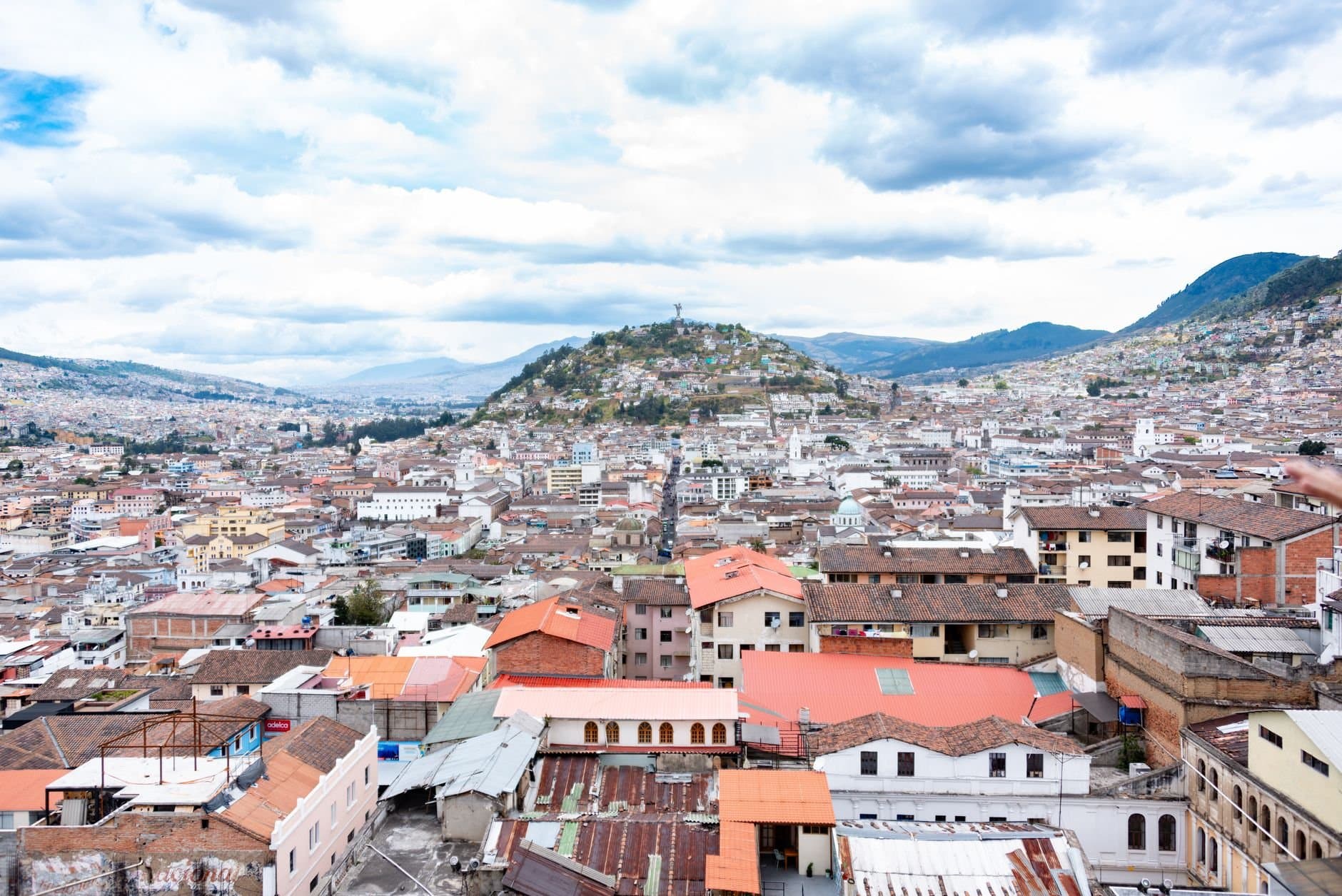 Aerial view showcasing Quito's urban landscape with rolling hills and colorful rooftops.