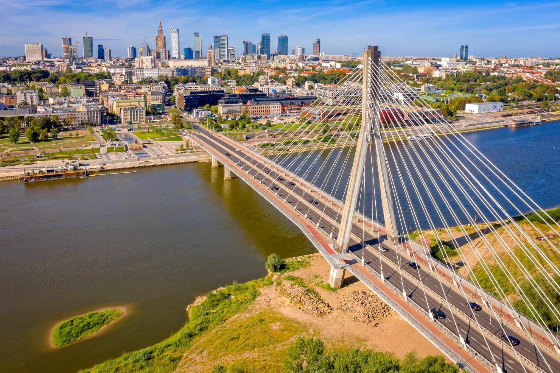Stunning aerial shot of Świętokrzyski Bridge spanning the Vistula River in Warsaw, Poland, with the city skyline.