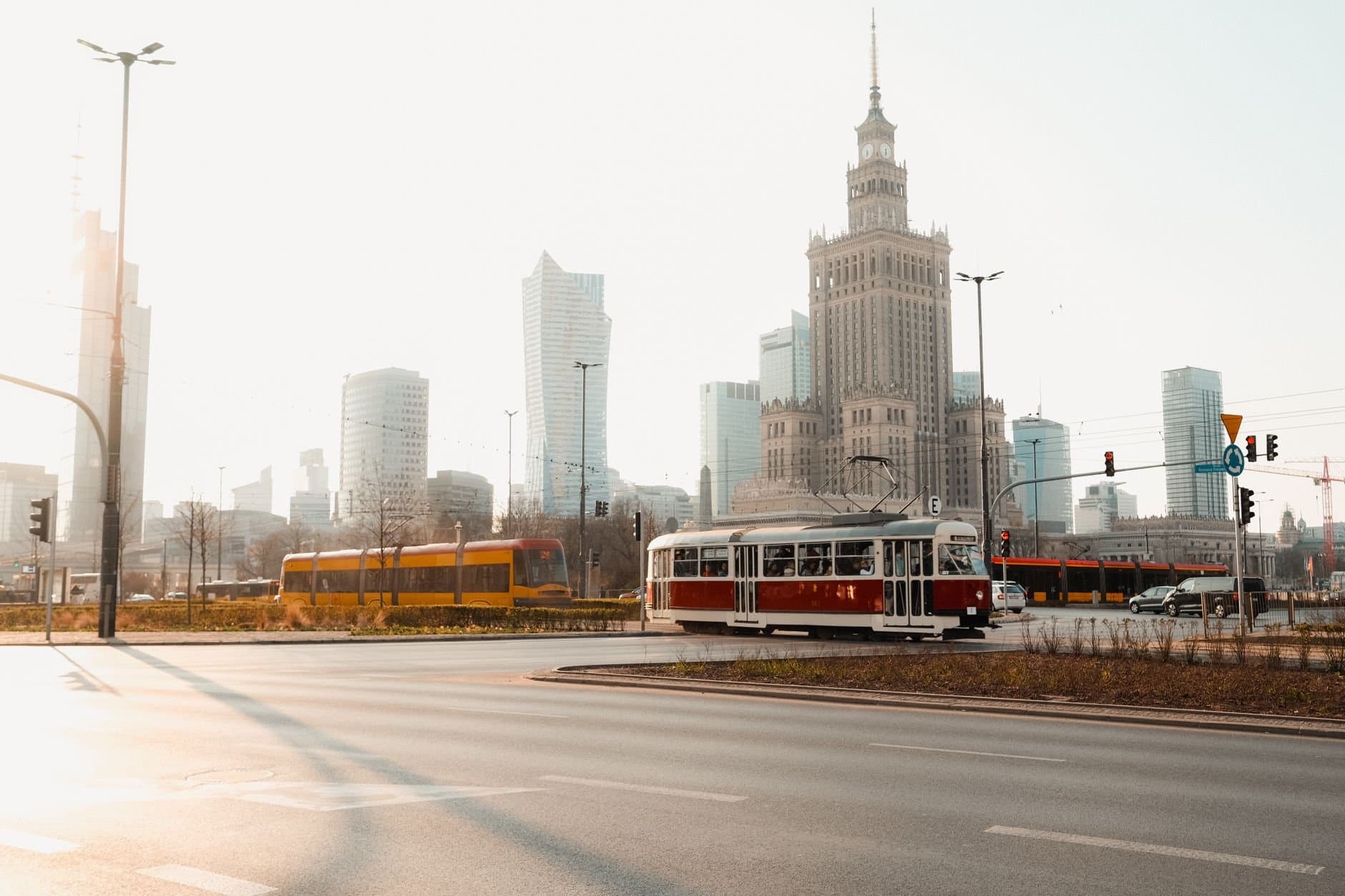 Historic tram passing through Warsaw's urban landscape with famous skyscrapers and the Palace of Culture and Science.