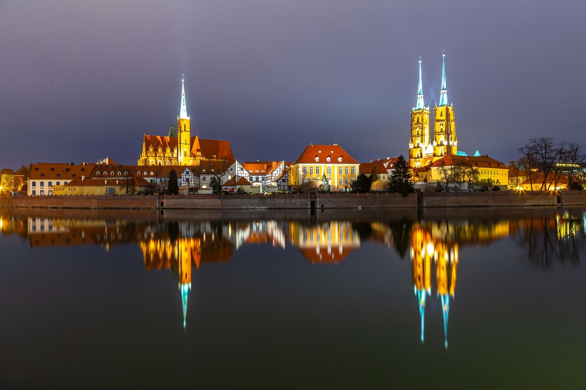 Stunning night view of Wrocław Cathedral illuminated and mirrored in the calm river.
