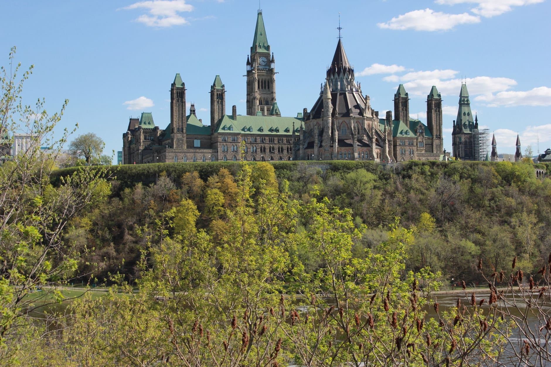 Picturesque view of the Ottawa Parliament Buildings in spring with lush greenery.