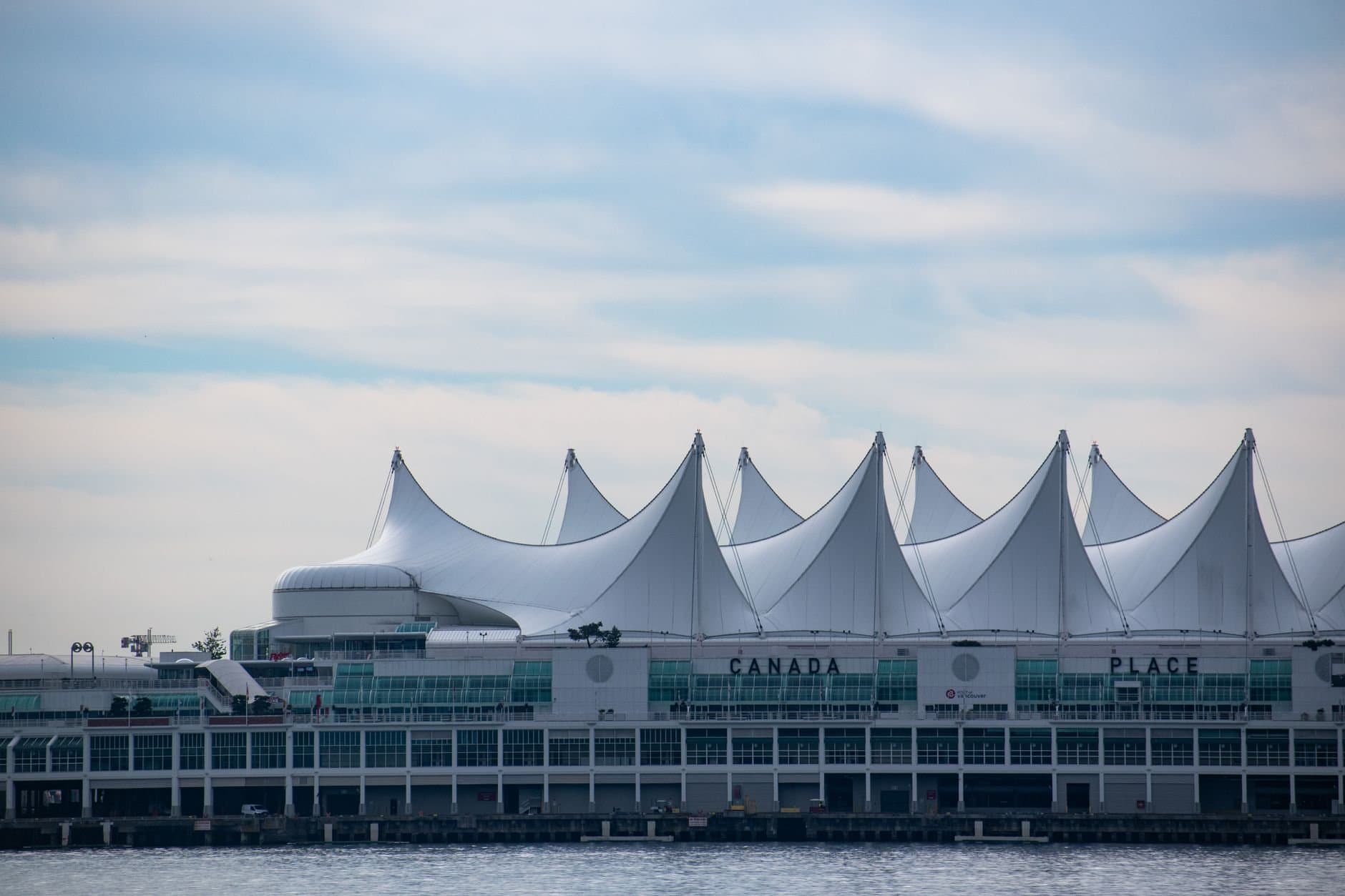 Iconic Canada Place building with its sail-like roof in Vancouver, BC against a blue sky.