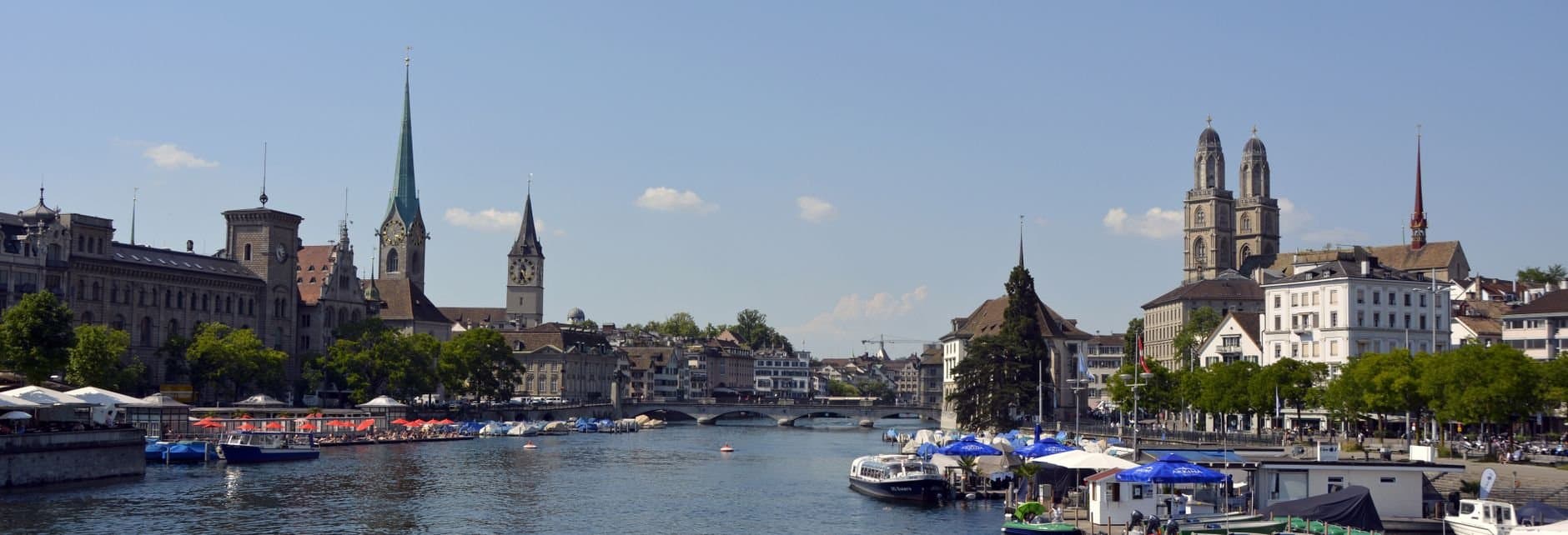 Explore Zurich's historic cityscape along the waterfront with iconic churches and bustling activity.