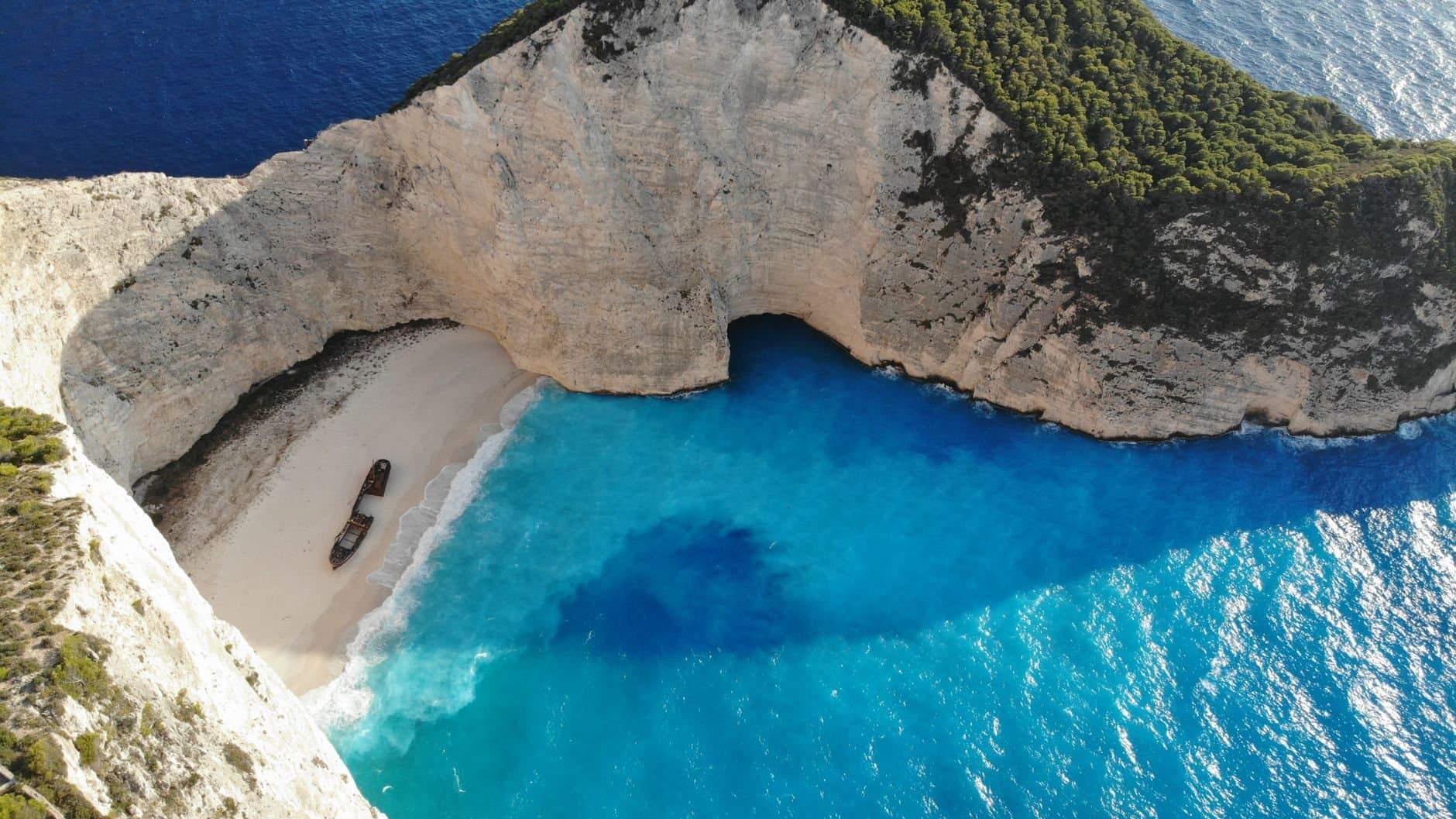 A breathtaking aerial view of Navagio Beach on Zakinthos Island, Greece, featuring vibrant blue waters and a shipwreck.