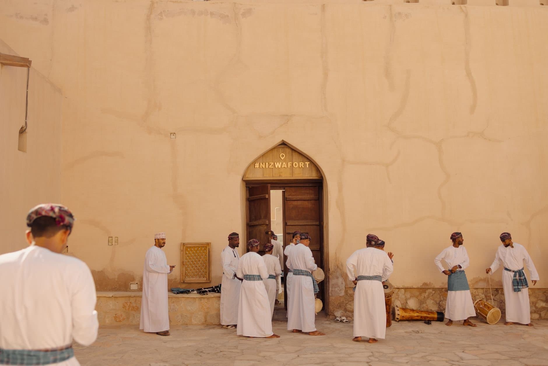Group of men perform a traditional Omani dance in front of Nizwa Fort, Oman.