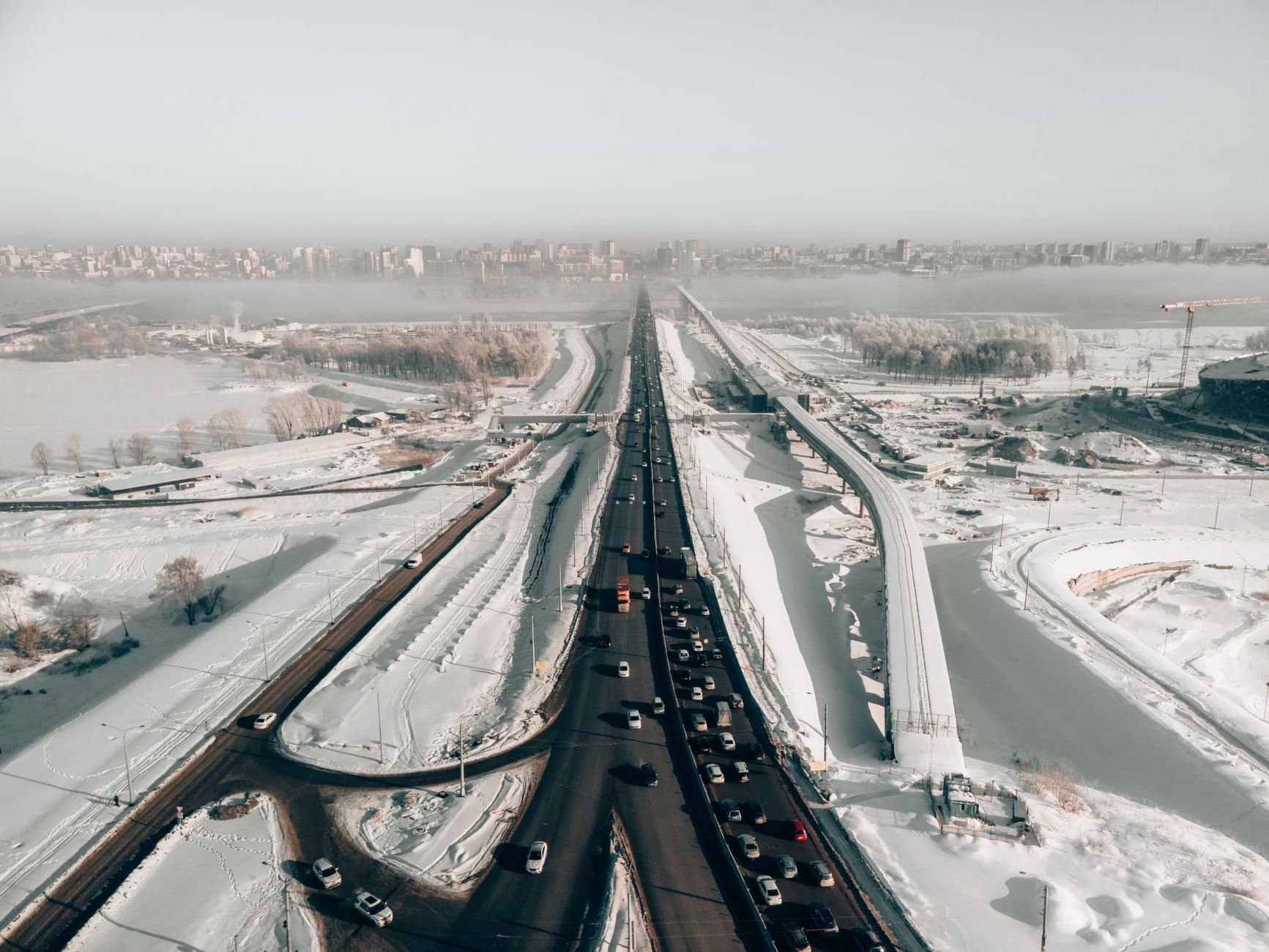 Aerial view of a snow-covered highway with traffic in winter, capturing the urban landscape of Novosibirsk, Russia.
