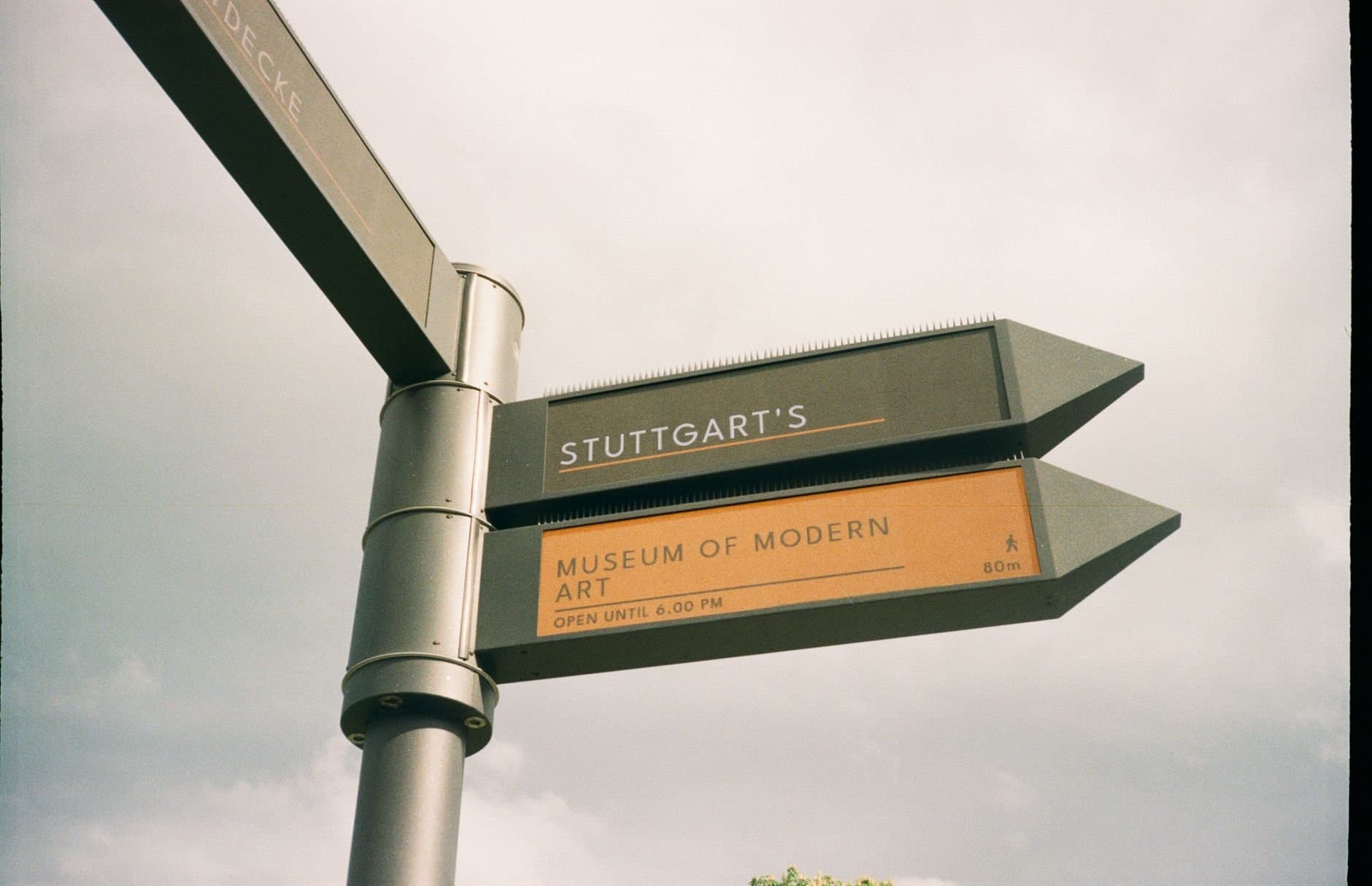 Signpost directing to Stuttgart's Museum of Modern Art under an overcast sky.