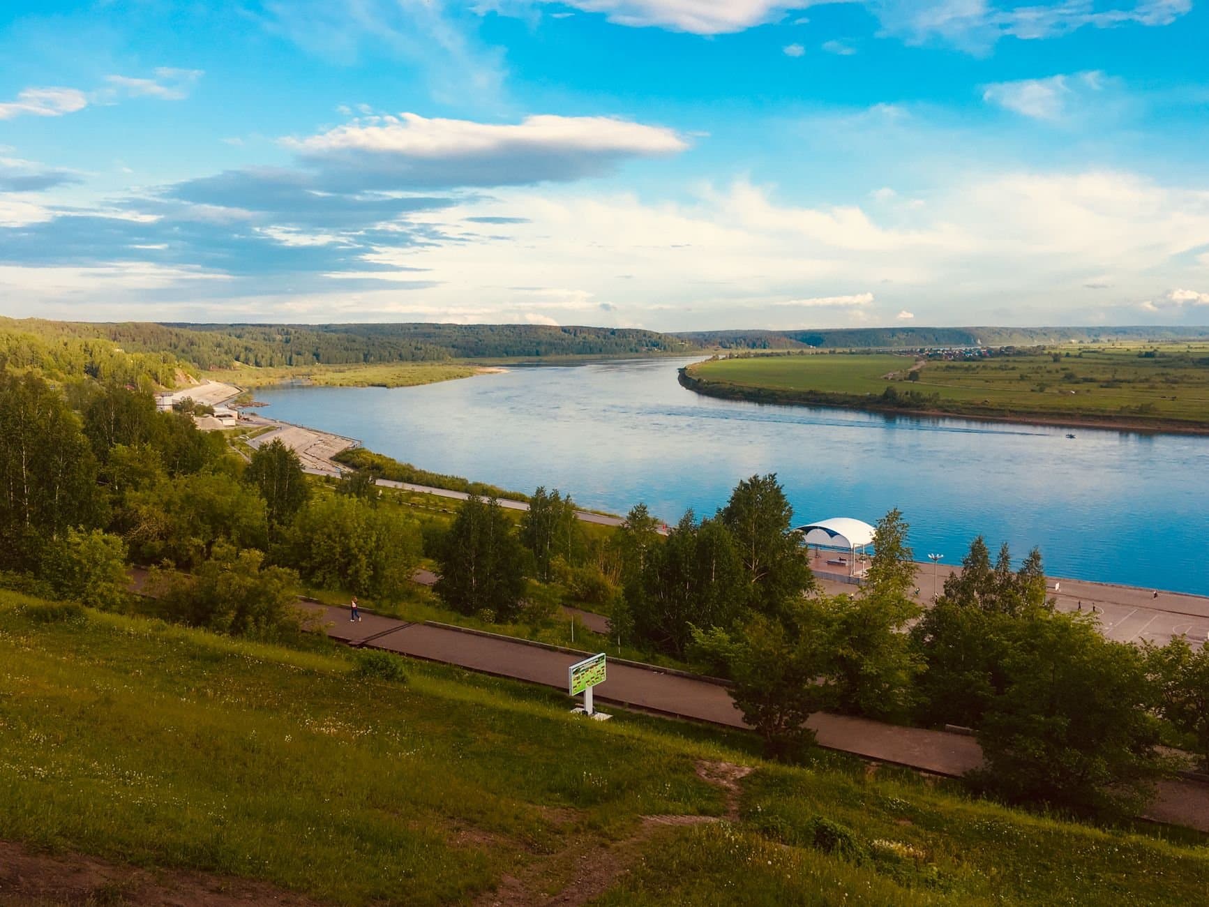 Idyllic summer view of Tom River in Tomsk, Russia with greenery and clear blue skies.